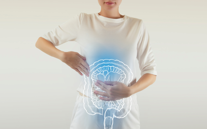 Mulher com desconforto abdominal e ilustração do intestino, representando como a saúde intestinal pode afetar o emagrecimento.
