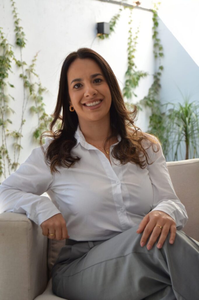 Dra. Ana Guariente sentada em consultório, com expressão acolhedora, representando seu atendimento próximo e personalizado.