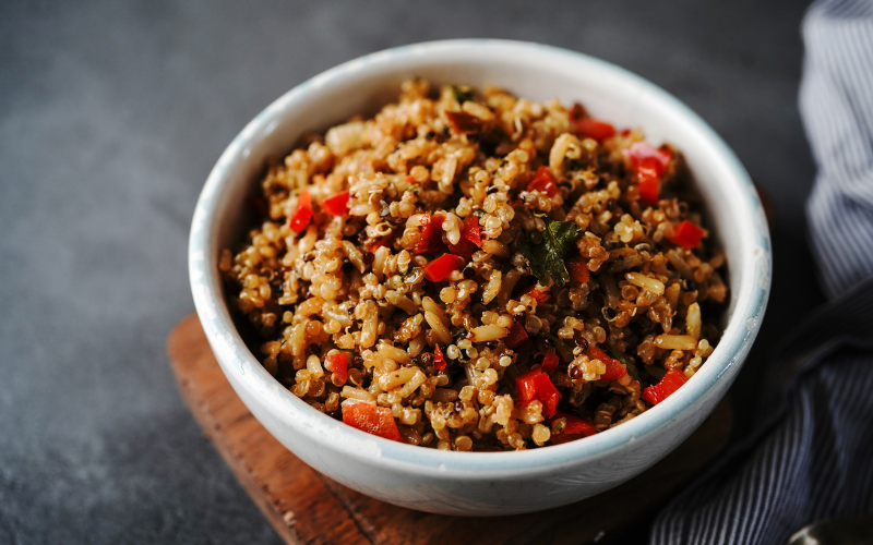 Arroz integral cozido com pimentões vermelhos e verdes em tigela branca.